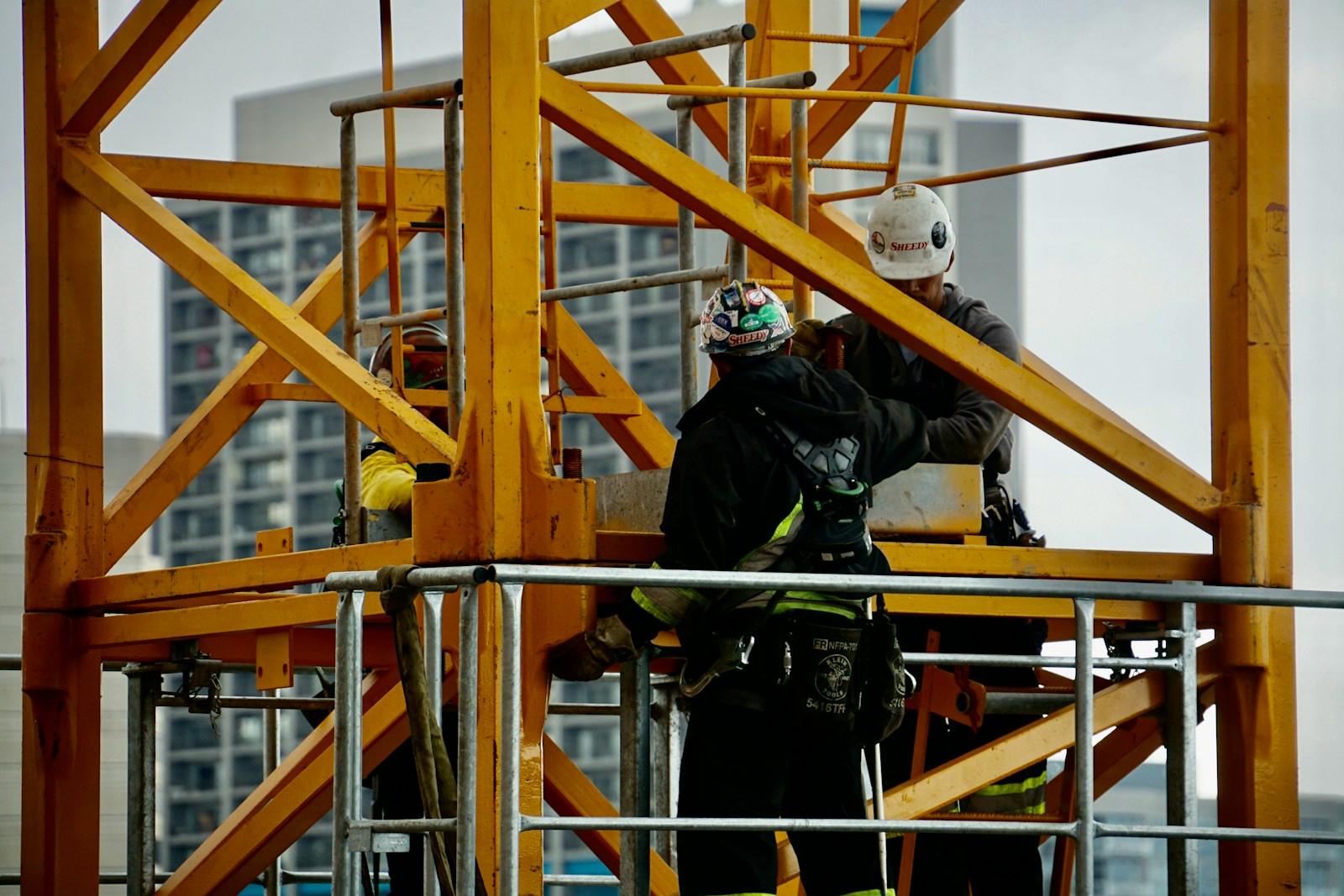 man in black jacket and helmet climbing orange ladder contractors